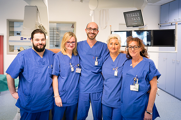 Gruppe von 5 Mitarbeitern in blauer Dienstkleidung in einem Flur der Radiologie Unimedizin Rostock
